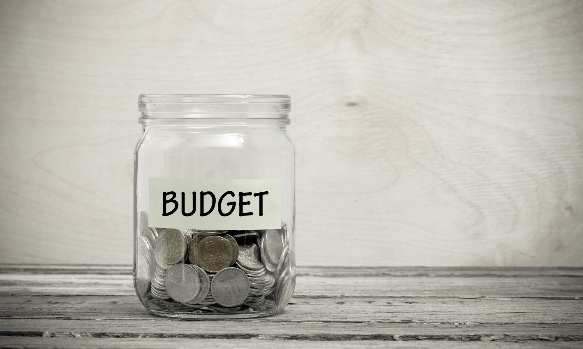 Jar filled with quarters that says "Budget" on the label.